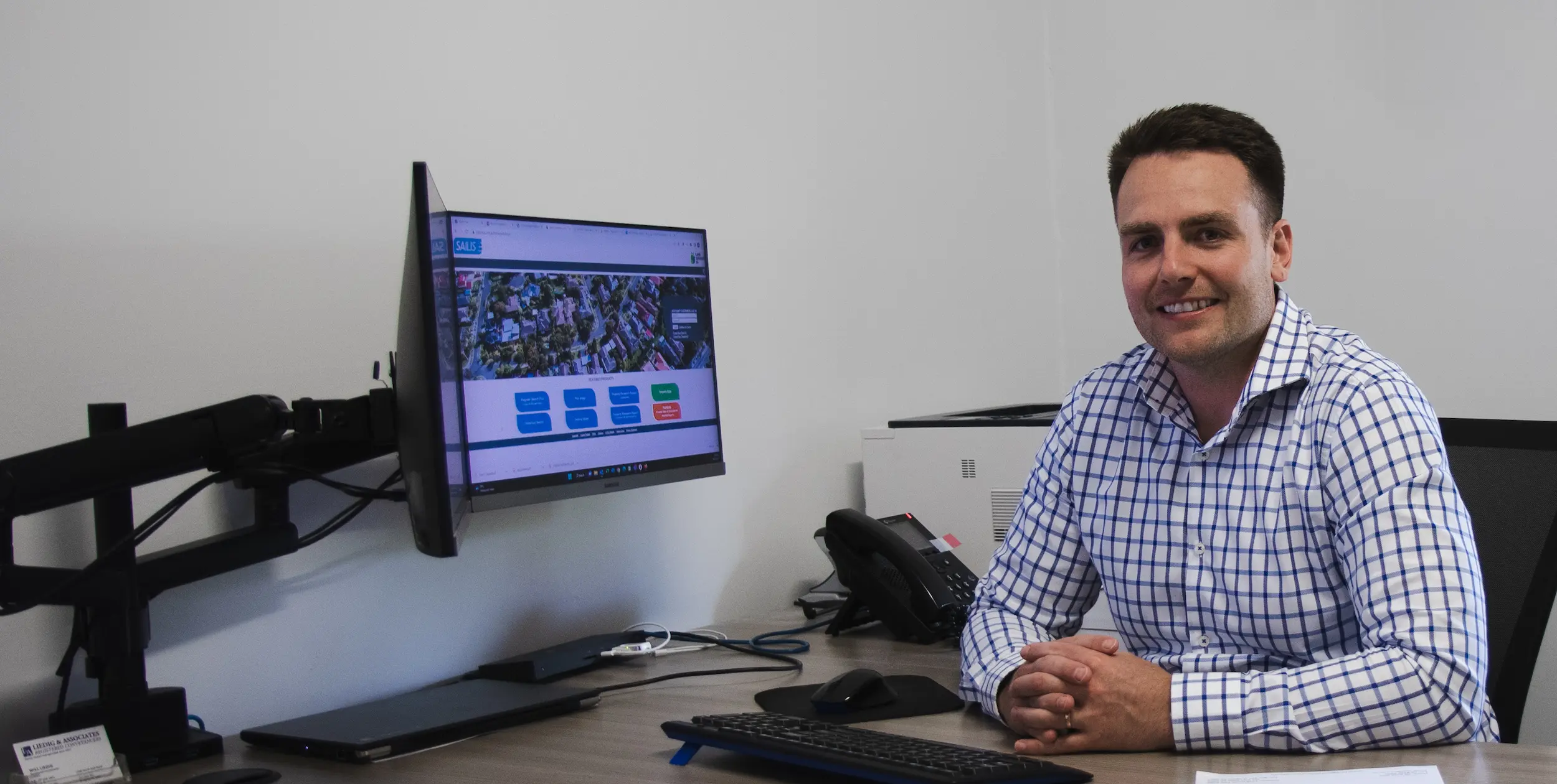 Will Liedig from Liedig and Associates sitting at his desk and smiling at the camera.